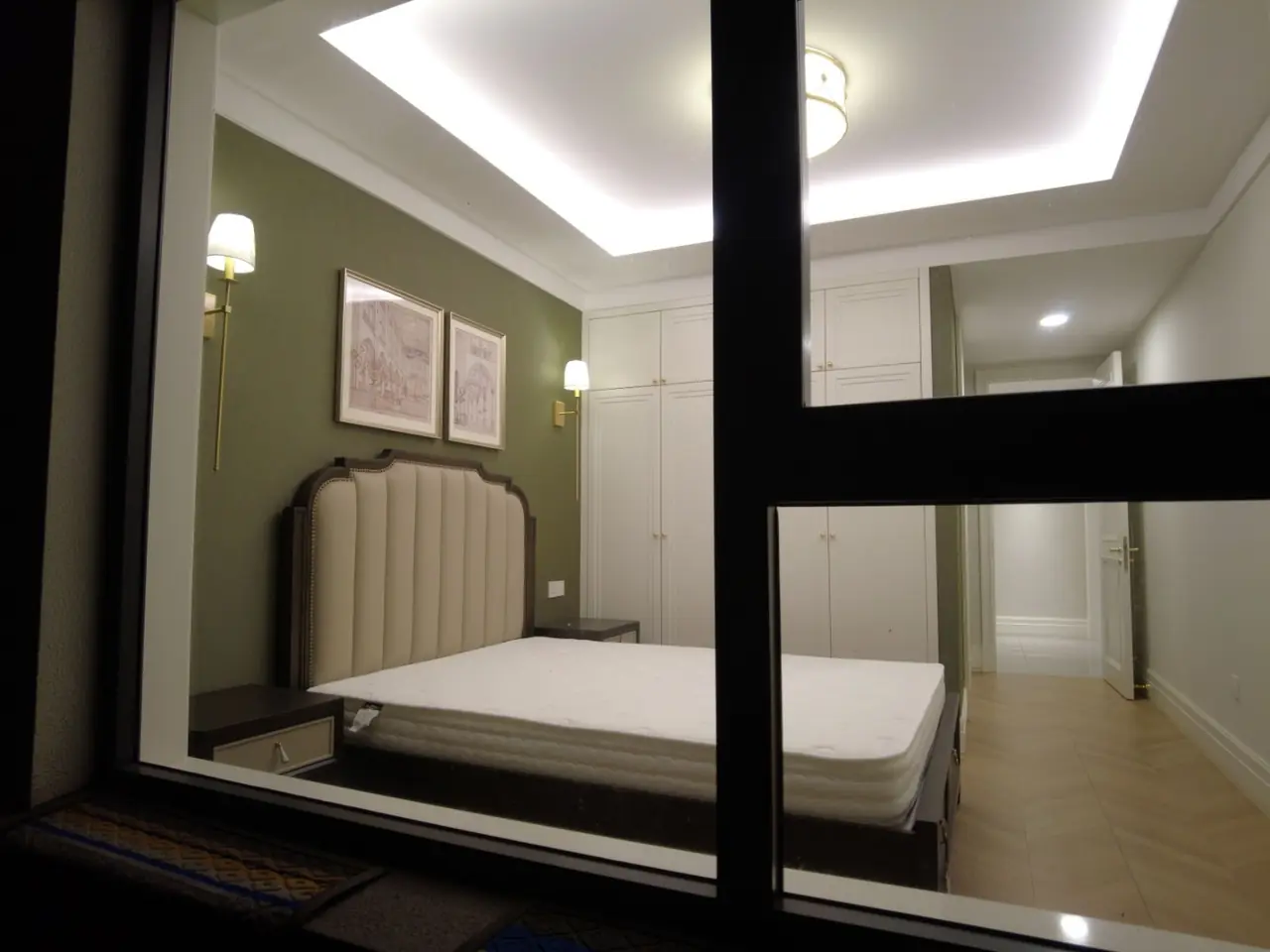 Bedroom with floor-to-ceiling fitted wardrobes, an upholstered bed and brass wall lamps